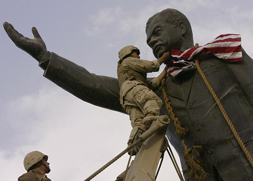 Cpl. Edward Chin of the 3rd battalion, 4th Marines regiment, set up the American flag on the face of the giant Saddam Hussein's statue before pulling it down, central Baghdad, April 9, 2003.